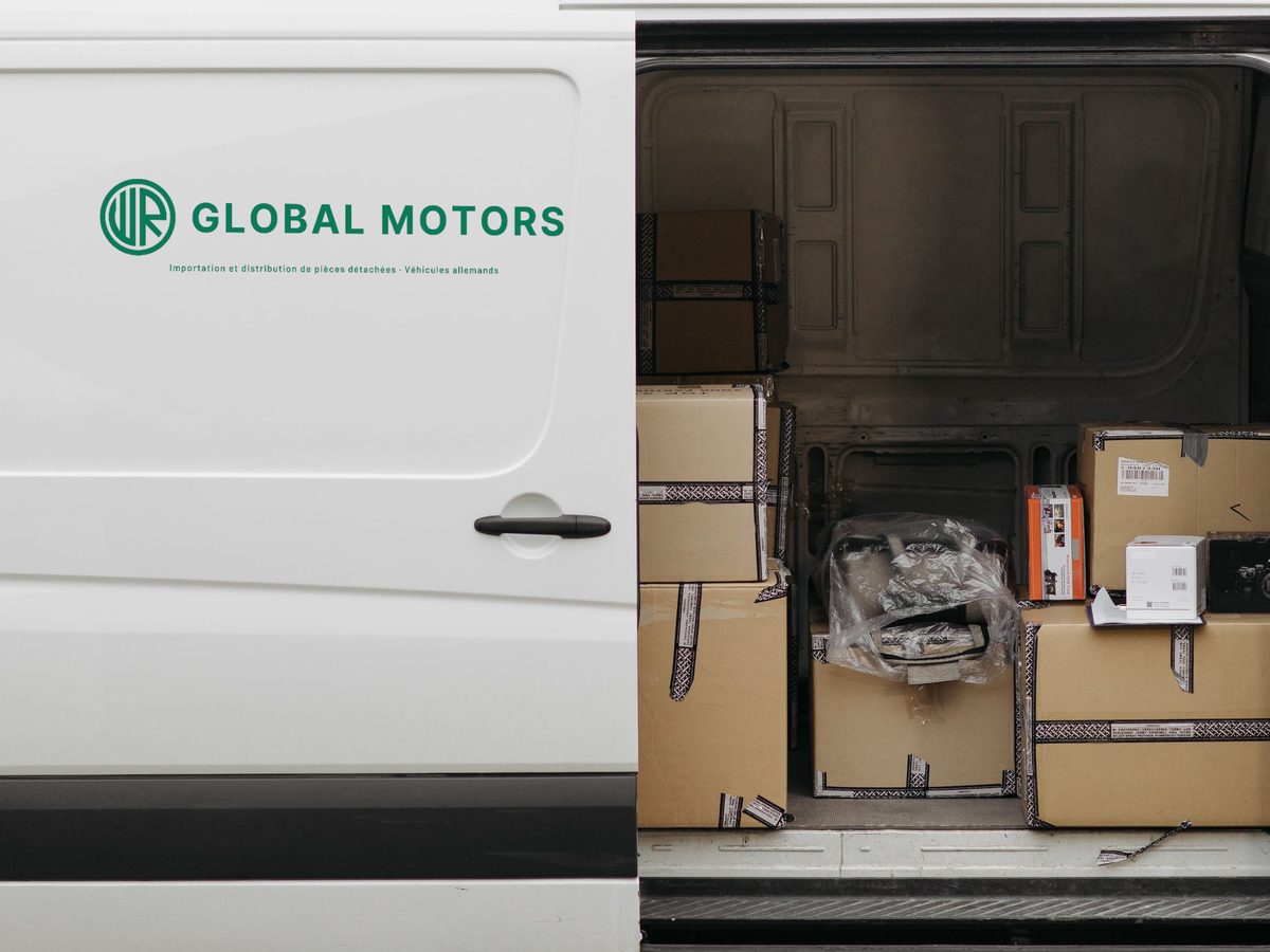 Camionnette de livraison au logo WR GLOBAL MOTORS, porte ouverte sur des colis